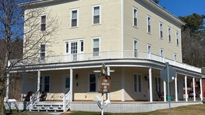A two-story building with a covered porch and a sign for Lake Gomser Inn. - Apt 2B Lake Bomoseen Inn “The Dog” with boat slip (Castleton)