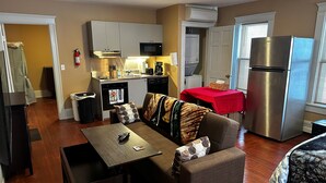 A compact living space with a kitchenette, a dining area, and a seating area with a couch and a table. - Apt 2B Lake Bomoseen Inn “The Dog” with boat slip (Castleton)