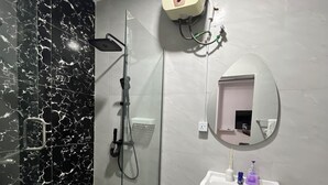 A modern bathroom with a glass-enclosed shower, a white sink with toiletries, and a toilet.