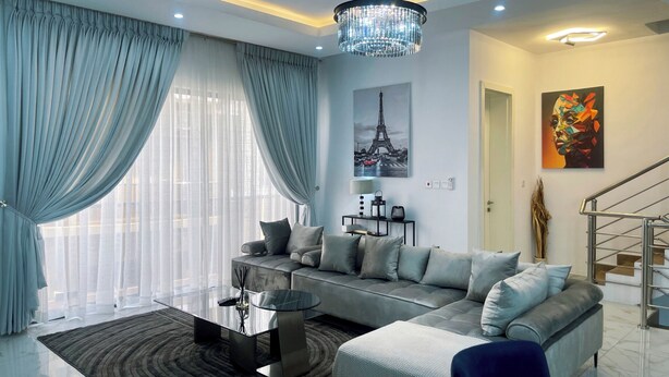 A modern living room with a sofa, a glass coffee table, and a chandelier.