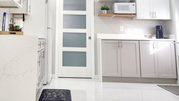 Una cocina moderna con armarios blancos, un microondas y una cafetera.