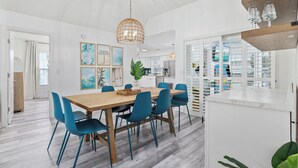 Una cocina moderna con armarios blancos, encimera de madera y sillas azules alrededor de una mesa de madera.
