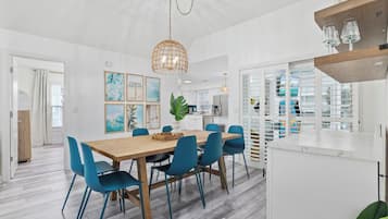 A modern kitchen with white cabinets, a wooden countertop, and blue chairs around a wooden table.