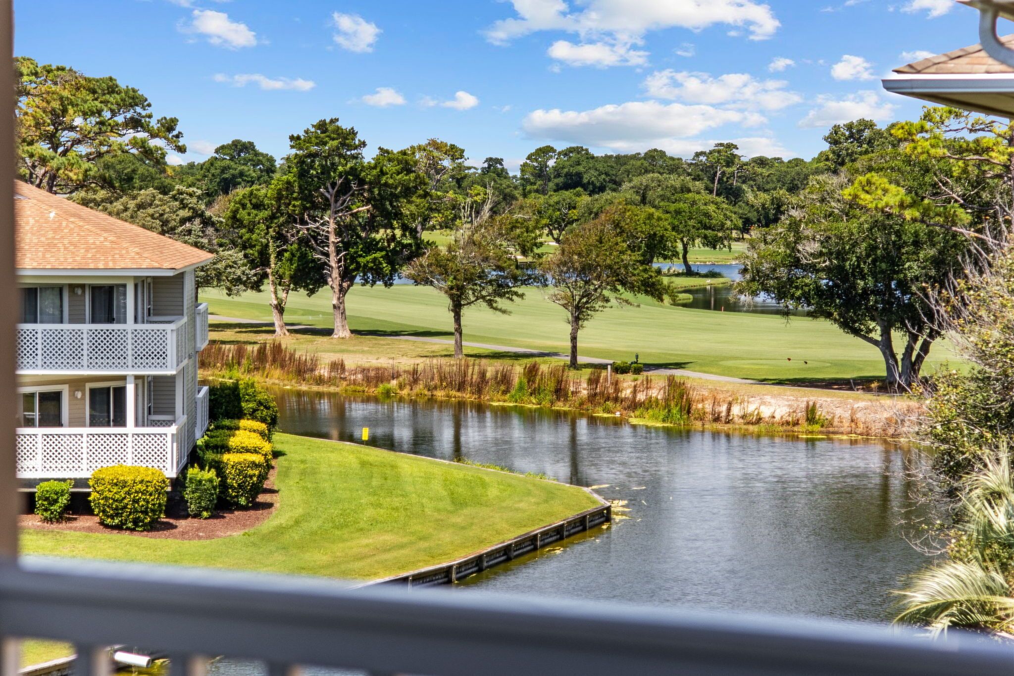 Una casa con porche y vista a un campo de golf y a un estanque.