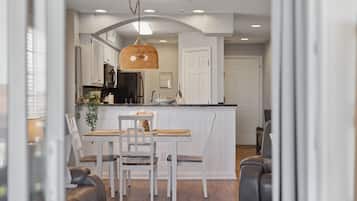 Una cocina moderna con armarios blancos, una isla central y una lámpara colgante.