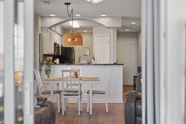 A modern kitchen with white cabinetry, a central island, and a hanging light fixture.