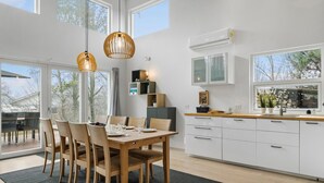Een moderne keuken met witte kasten, een houten eettafel en hanglampen.