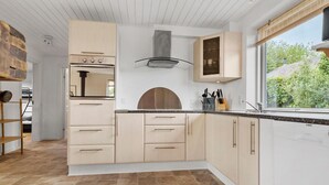 A modern kitchen with light wood cabinets, a built-in oven, and a large window with a view of greenery. - 4 bedroom gorgeous home in Gråsten (Gråsten)