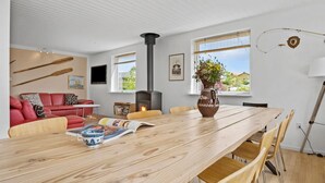 A modern living room with a wooden dining table, red leather sofa, and a fireplace. - 4 bedroom gorgeous home in Gråsten (Gråsten)