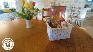 Una mesa de madera con un jarrón blanco lleno de flores y una cesta de mimbre.
