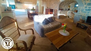 Una sala de estar acogedora con un sofá, sillones de mimbre, una mesa de centro de madera y una chimenea de piedra.