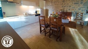 Una cocina moderna con armarios blancos, una mesa de comedor con sillas y una pared de piedra.