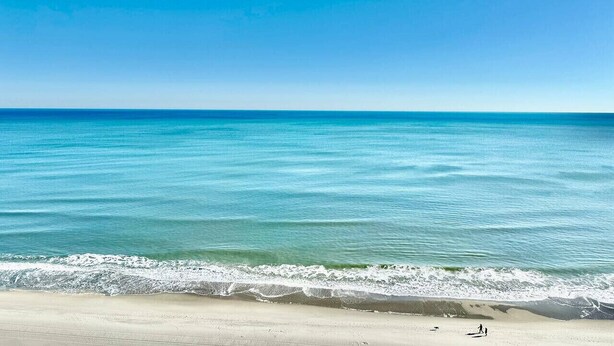 Een strand met helderblauw water en een zandstrand.