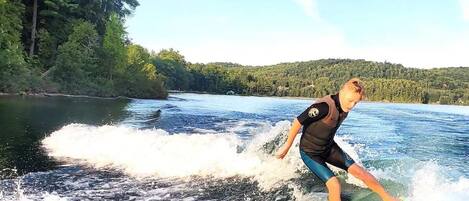 A person wakeboarding on a lake with trees and hills in the background.