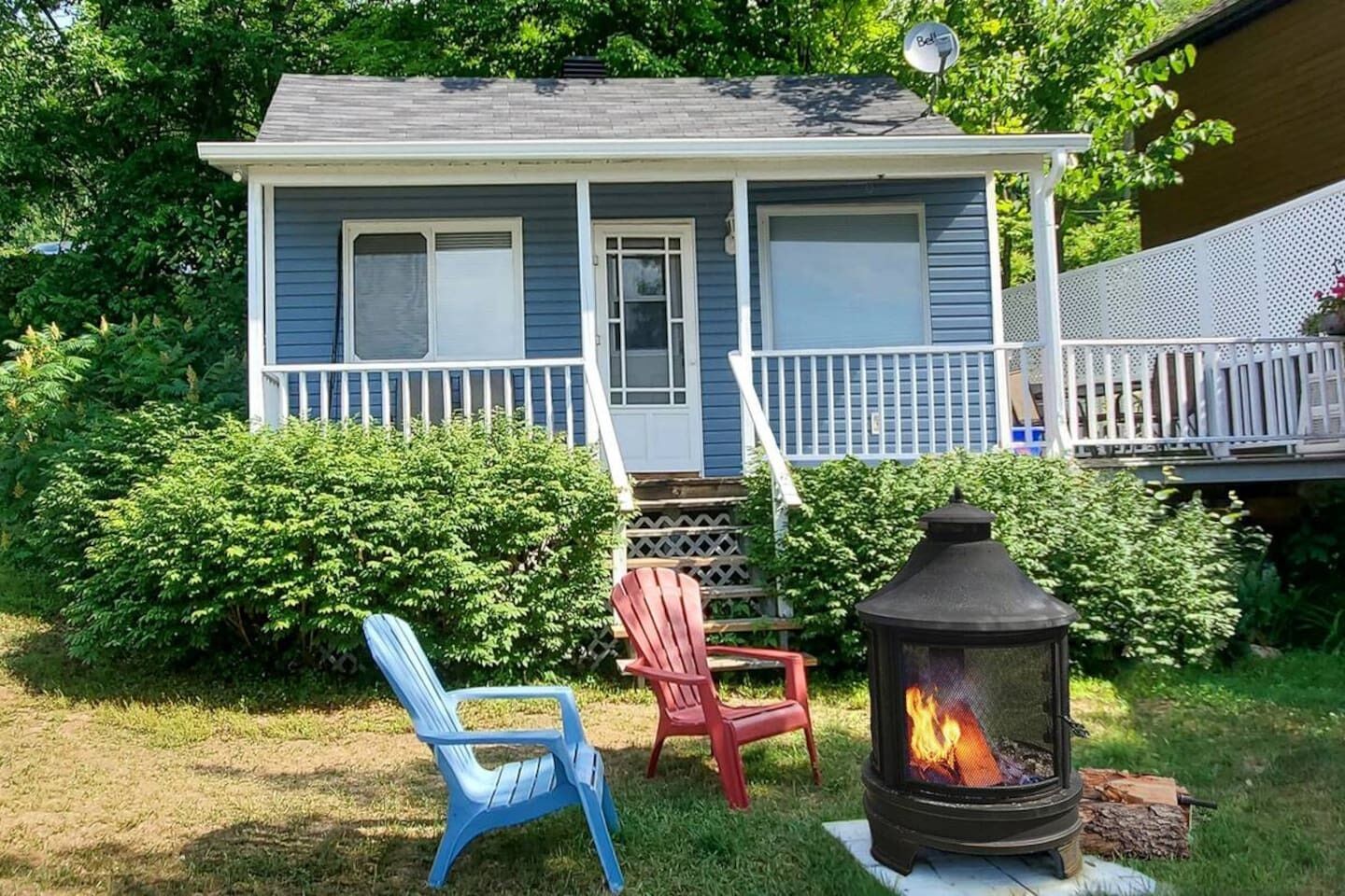 A house with a porch, a fire pit, and two chairs.