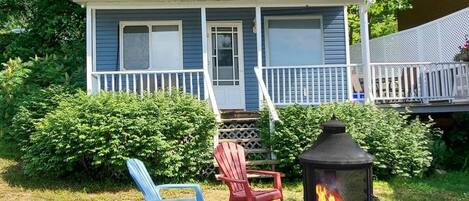 A house with a porch, a fire pit, and two chairs.