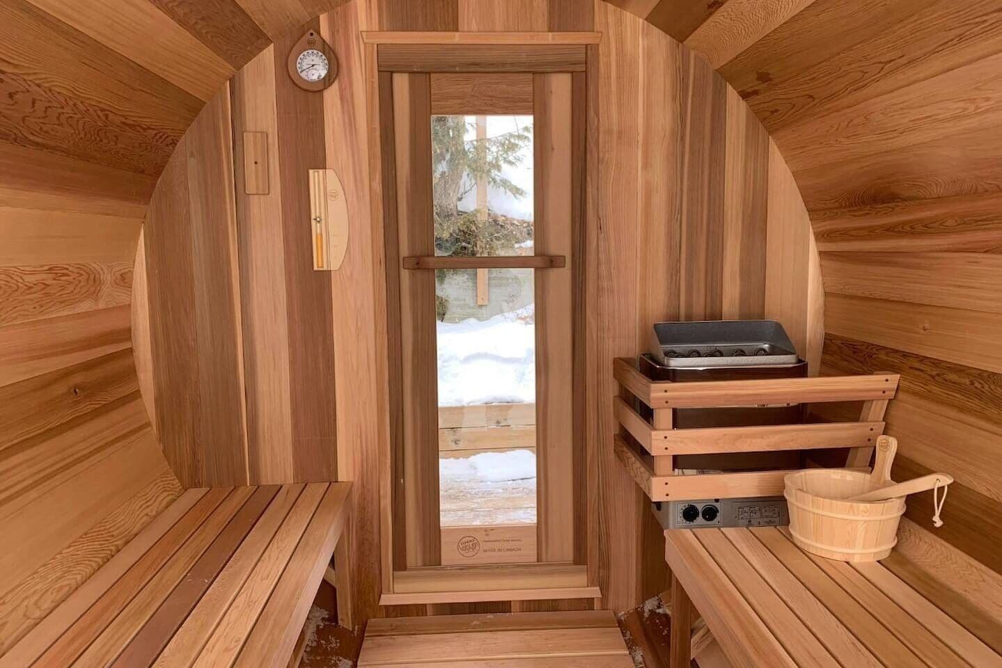 Una sauna con pareti in legno, una panchina, uno scaldasalviette e una finestra vista sulla neve.