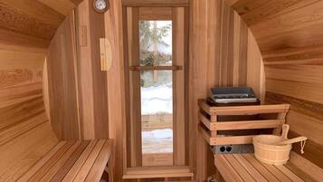Una sauna con pareti in legno, una panchina, uno scaldasalviette e una finestra vista sulla neve.