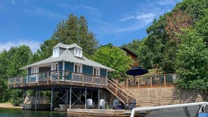 A waterfront house with a balcony, outdoor seating, and a dock. - Rustic Cabin on Lac McGregor (Val-des-Monts)