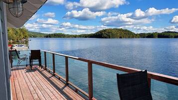 Relax on the deck overlooking the calm lake, surrounded by a forested hill.