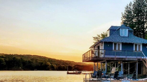 A lakeside house with a balcony and a dock extending into the water. - Rustic Cabin on Lac McGregor (Val-des-Monts)