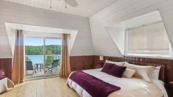A bedroom with a large bed, a view of a balcony, and a window with blinds.