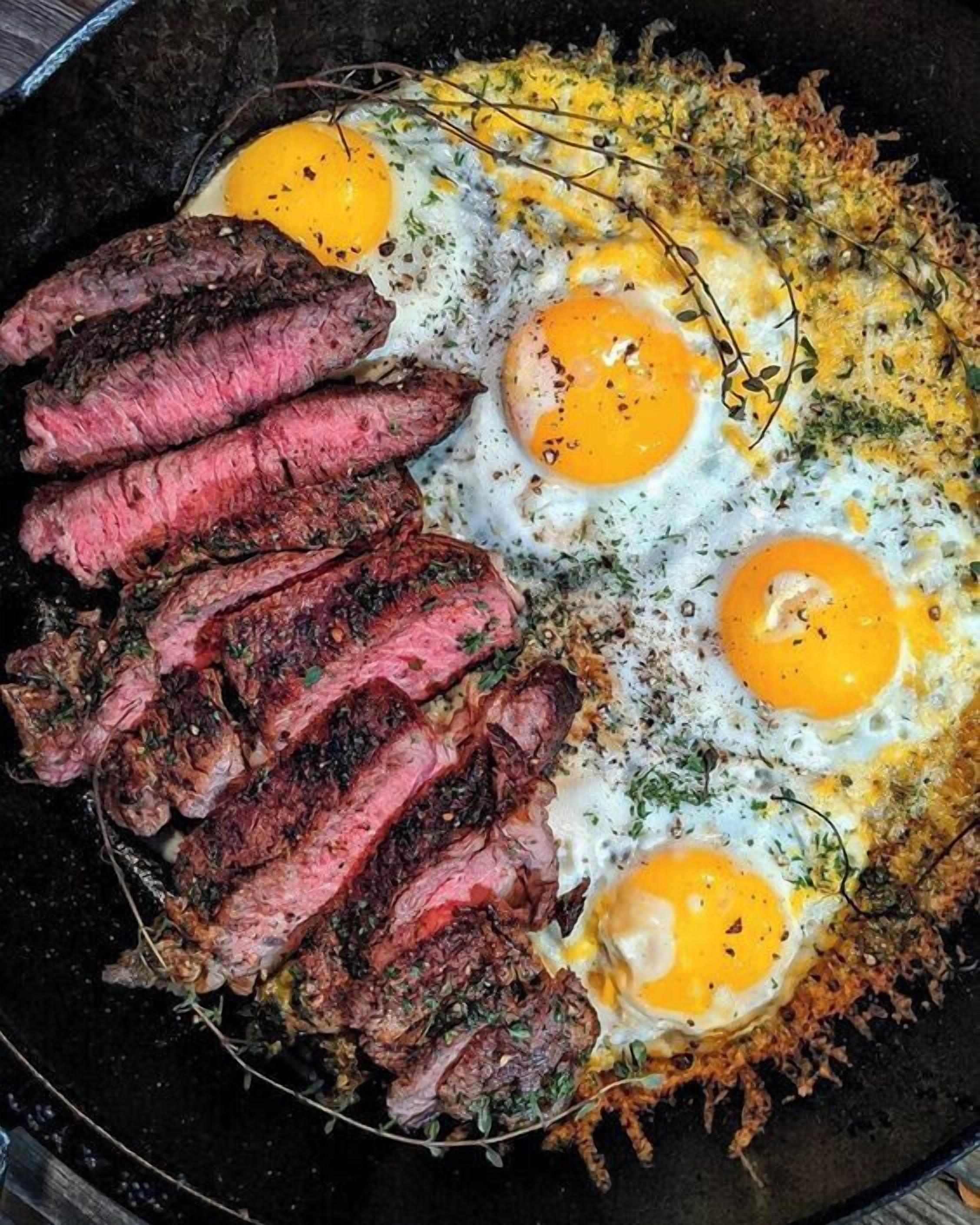 Una sartén con bistec y huevos fritos.