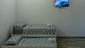 Un dormitorio con cama, ventilador de techo, televisor en la pared y lámpara.