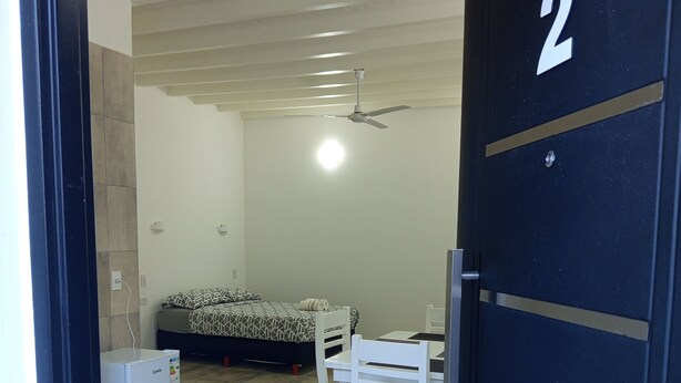 Una habitación con cama, escritorio, silla y refrigerador.