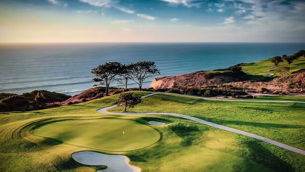 Un campo de golf con vista al océano y un cielo despejado.