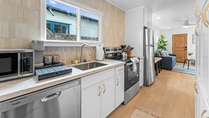 Una cocina moderna con electrodomésticos de acero inoxidable, lavavajillas y ventana con vistas a una terraza.
