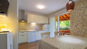 Una cocina compacta con armarios blancos, lavavajillas integrado y un comedor con mesa y sillas.