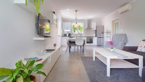 Una cocina moderna con armarios blancos, un comedor con mesa y sillas blancas, y una sala de estar con un sofá blanco y una mesa de centro.