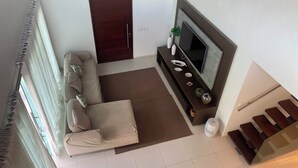 Een moderne woonkamer met een bank, televisie en decoratieve objecten.