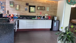 Een moderne keuken met een centraal eiland, een fornuis en een spoelbak. Diverse keukengerei en apparaten zijn aanwezig, waaronder een koffiezetapparaat en een broodrooster.