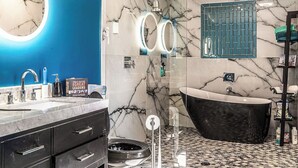 Ein modernes Badezimmer mit einer freistehenden schwarzen Badewanne, einem großen Spiegel mit runden Leuchten und einer blauen Akzentwand.