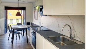 Una cocina moderna con una isla grande, horno empotrado y pileta de acero inoxidable.