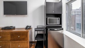Ein gemütlicher Raum mit Flachbildfernseher, Mikrowelle, Kühlschrank und einem Holzkasten.