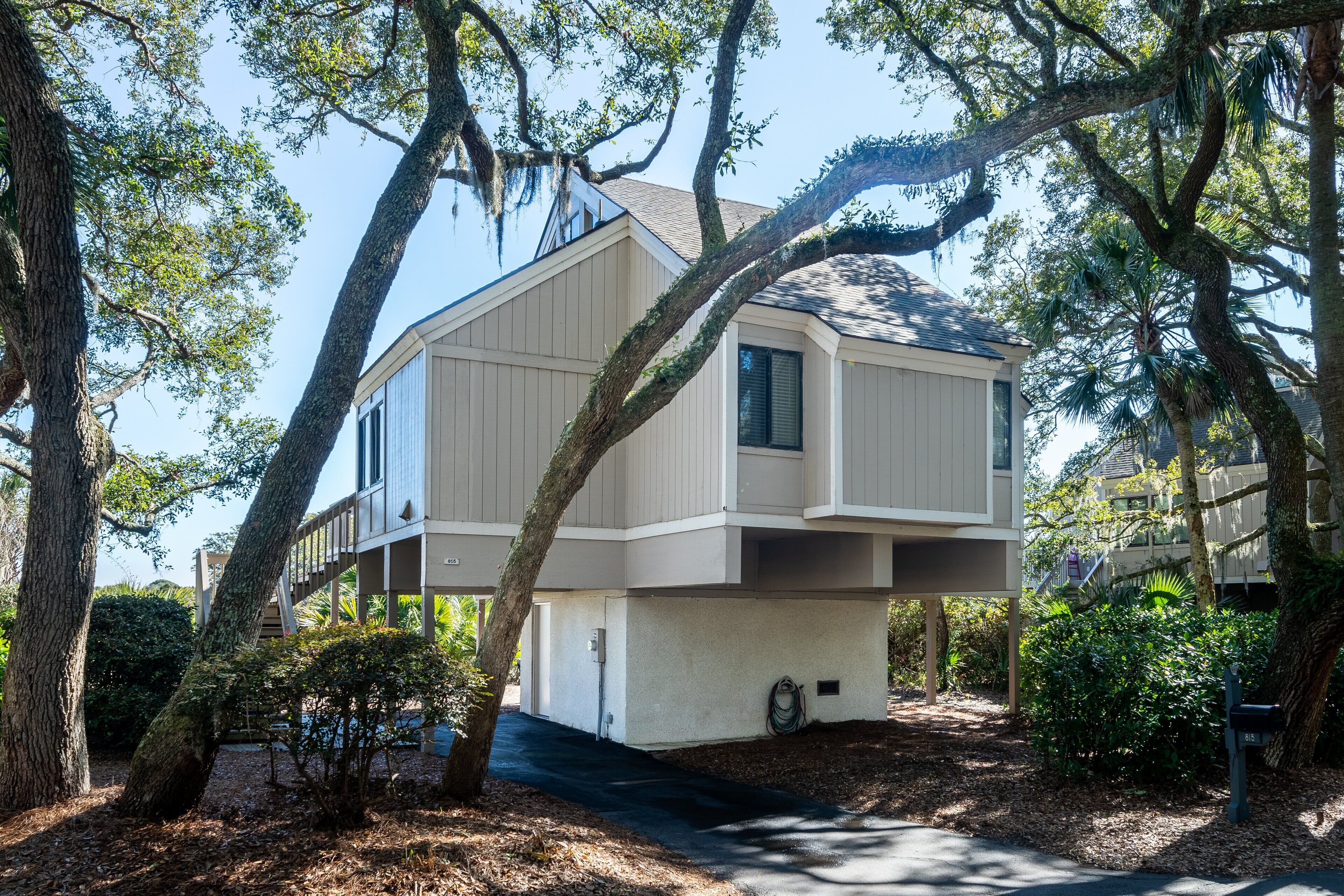 A modern two-story house with a flat roof, surrounded by mature trees and a well-maintained garden.