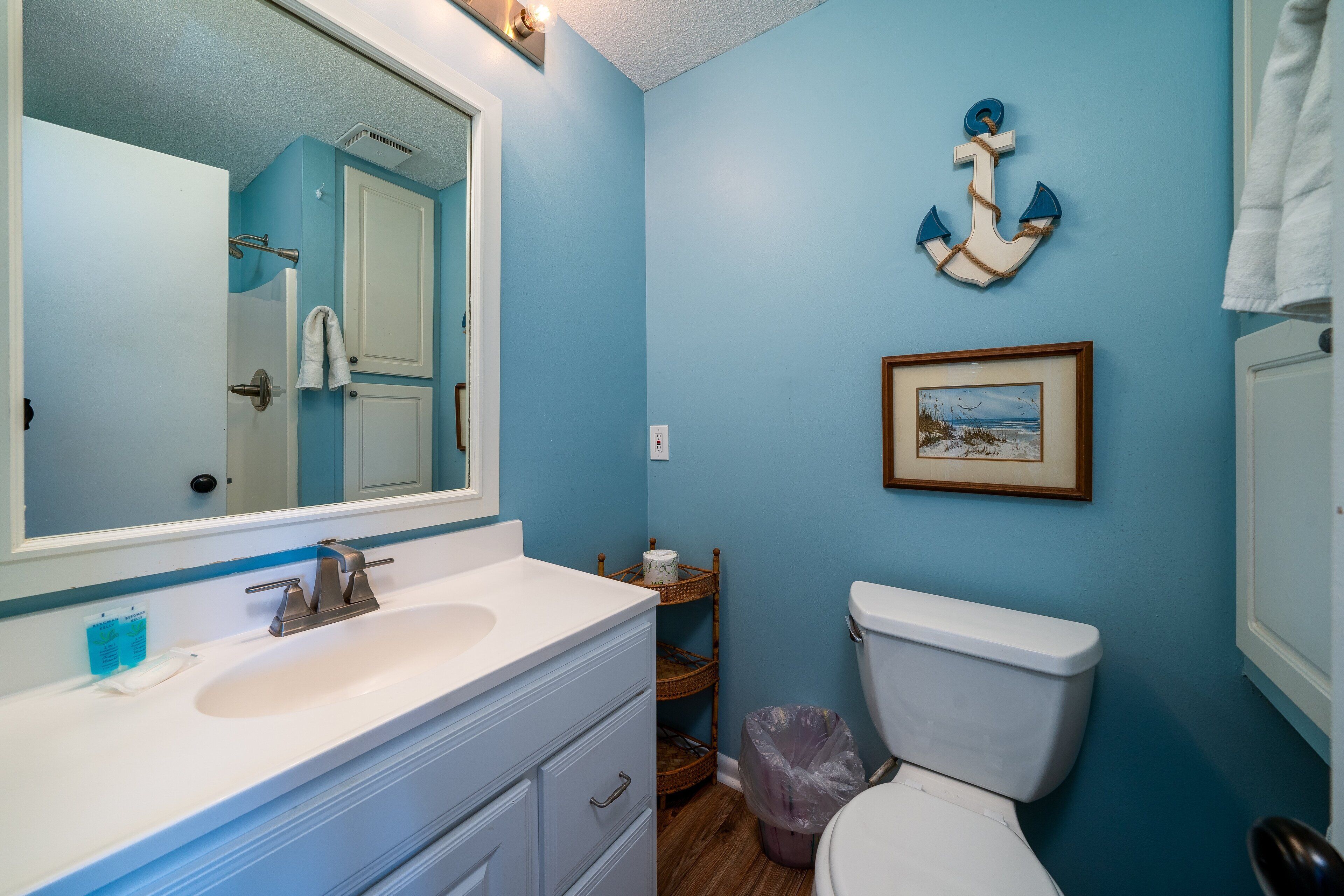 A bathroom with a white sink, a mirror, a toilet, and a blue wall.