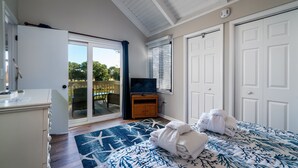 A bedroom with a bed, a TV, a wardrobe, and a sliding glass door leading to a balcony. - 2BR/2BA + Loft Cottage! Close to Beach! Golf Course Views! Amenity access Available! (Seabrook Island)
