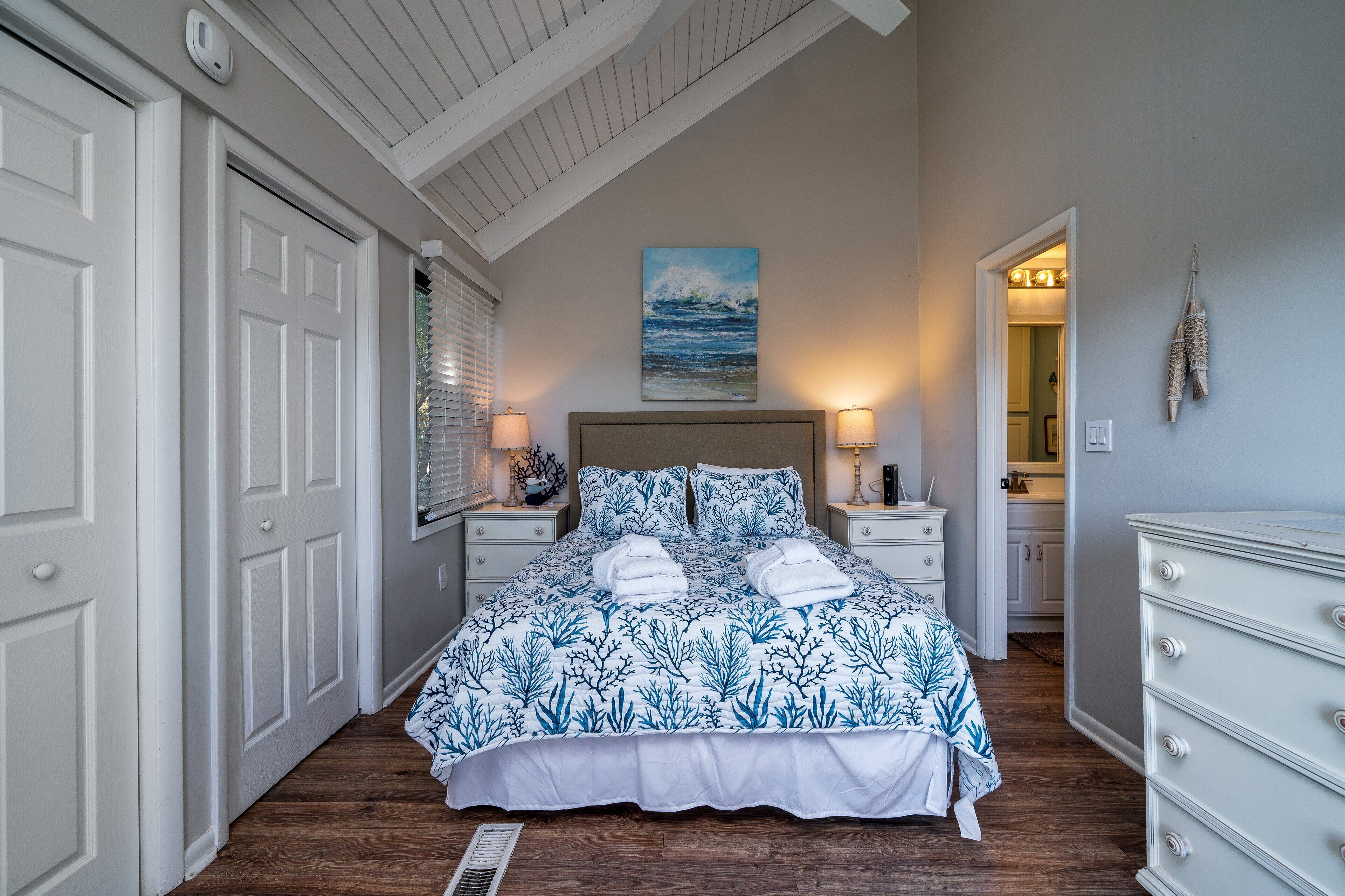 A bedroom with a bed, two bedside tables, a nightstand, a dresser, and a painting on the wall.