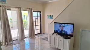 Una sala de estar con televisor, un aparador y una puerta corrediza de vidrio.