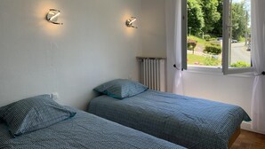 Et soveværelse med to senge, en radiator og et vindue med gardiner.