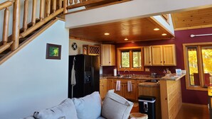 A spacious living area with a wooden staircase, a kitchen with wooden cabinets, and a dining area. - Rock Lake Retreat: Sun, Water & Relaxation – The Ultimate Summer Escape! (Iron Mountain)