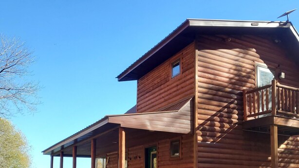A wooden cabin with a balcony, a front door, and a staircase leading to the main entrance. - Rock Lake Retreat: Sun, Water & Relaxation – The Ultimate Summer Escape! (Iron Mountain)