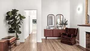 A room with a wooden floor, a large plant, a brown armchair, a wooden cabinet, and a fireplace. - Tranquil Coogee Retreat with large backyard & pool (Coogee)