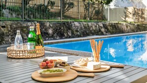 A poolside table with a bottle of champagne, a bottle of wine, and various snacks. - Tranquil Coogee Retreat with large backyard & pool (Coogee)