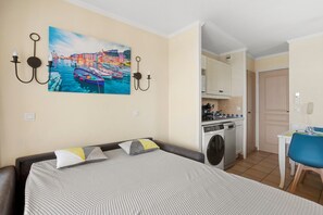 Une chambre à coucher avec un lit, un tableau, un lave-linge et un coin repas.