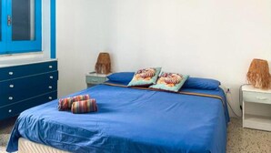 Une chambre à coucher avec un lit, des oreillers, une lampe et une commode.